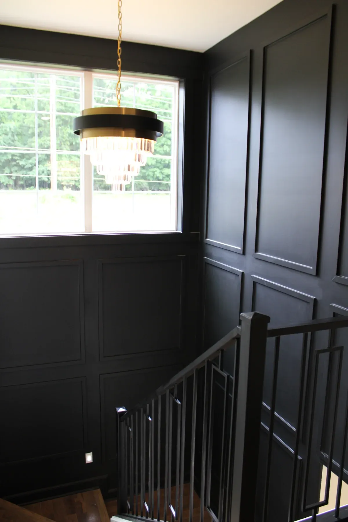 Looking down the stair case featuring a habging light accent.