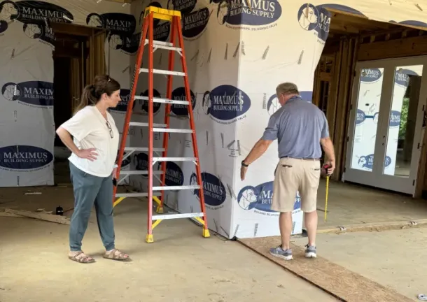 Sean with customer measuring space in kitchen area during construction.